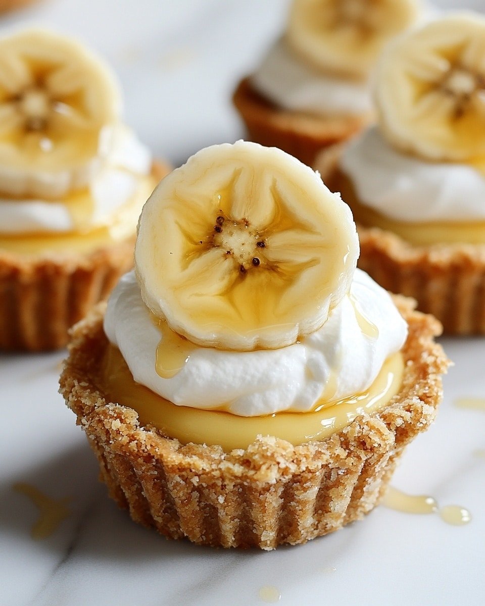 The image shows a small dessert cup with three clear layers. The bottom layer is a crumbly, golden-brown crust that forms the cup shape. Above it is a thick pale yellow creamy filling that looks smooth and shiny. The top layer is a thick white whipped cream with pointed peaks. On top of the whipped cream, there are two round slices of a yellow fruit with a star-like pattern in the middle. A shiny, light amber syrup drips over the whipped cream between the fruit slices. The dessert sits on a white marbled surface with other similar desserts in the background, and a woman's hand is gently holding one of the cups. photo taken with an iphone --ar 4:5 --v 6.1